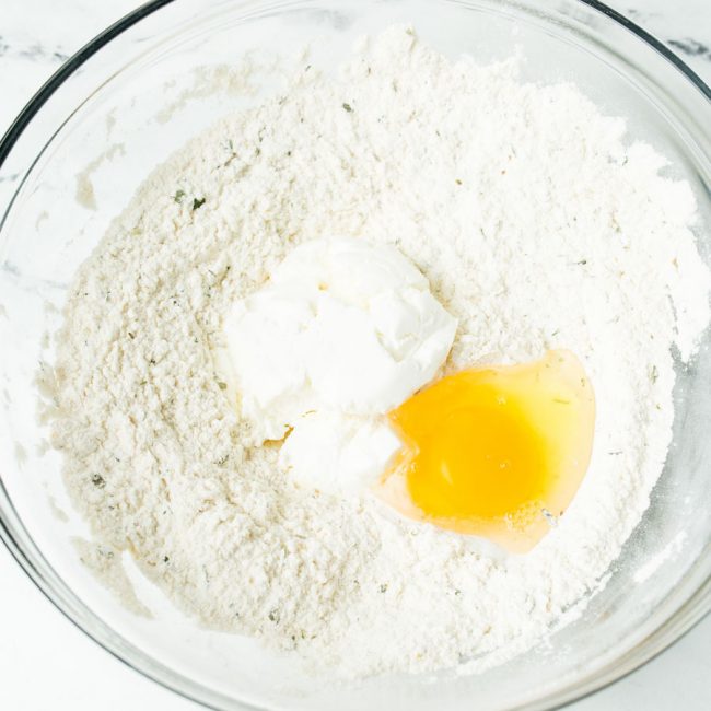 Dry ingredients for breadsticks in a bowl with yogurt and an egg.