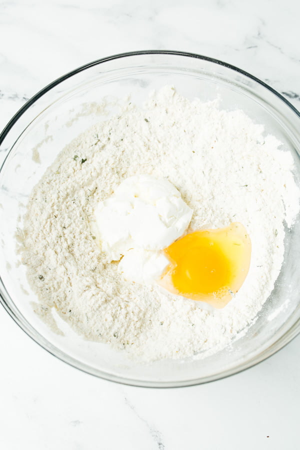 Dry ingredients for breadsticks in a bowl with yogurt and an egg.