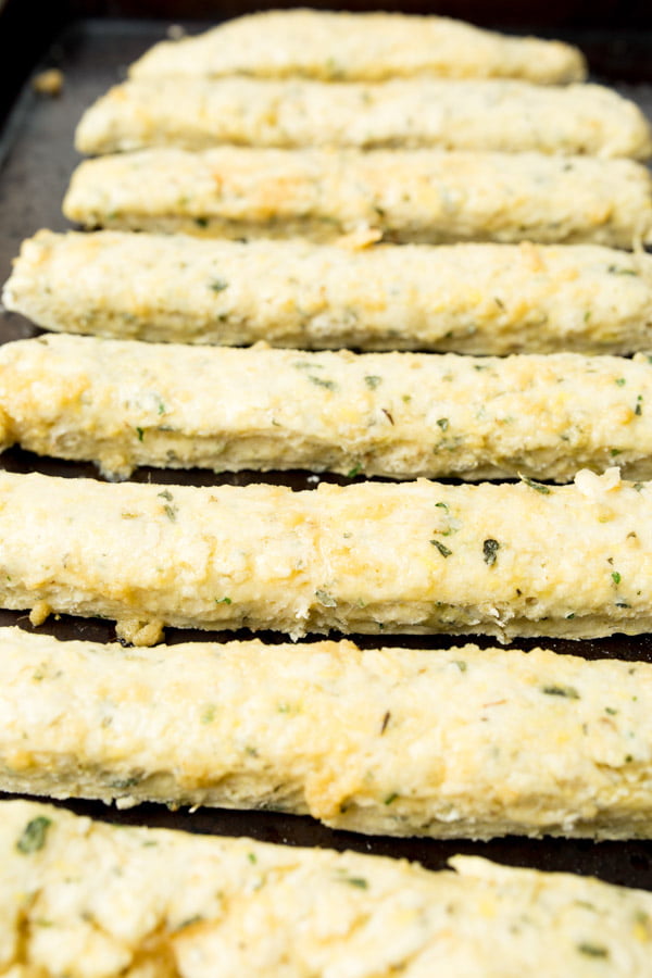 Baked gluten free breadsticks on a baking sheet.