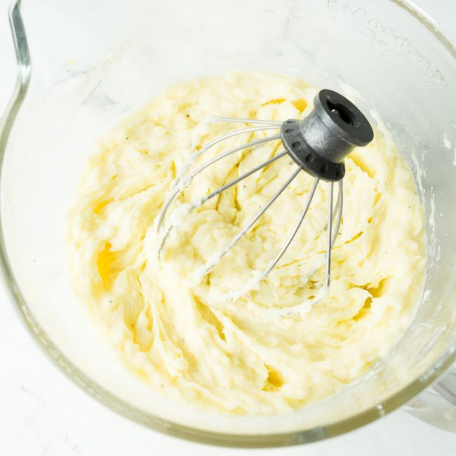 An upclose image of mashed potatoes whipped with a kitchen aid whisk attachment