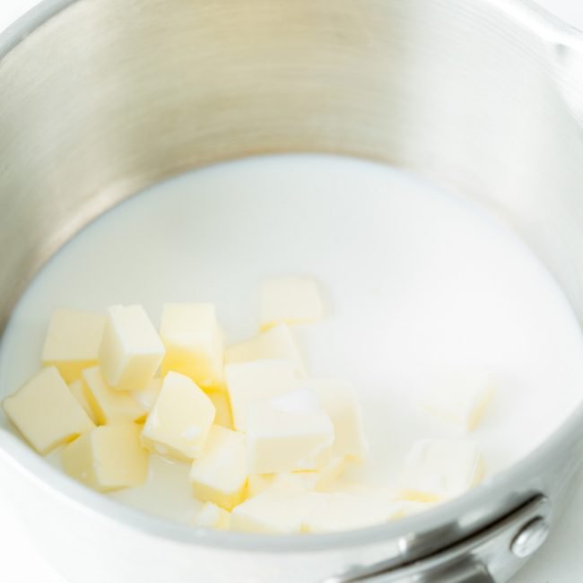 A close up image of butter melting in a pot of milk
