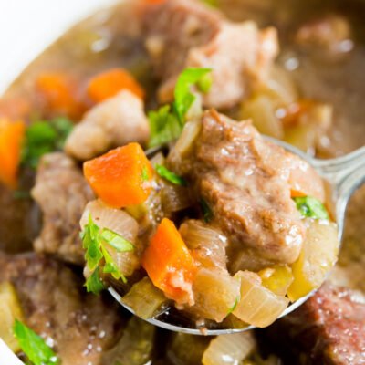 A close up image of a spoon and bowl full of beef stew