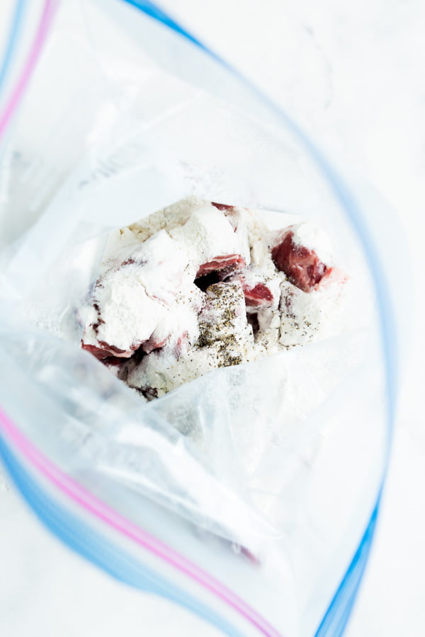 A ziploc bag of steak bites, flour, and seasoning