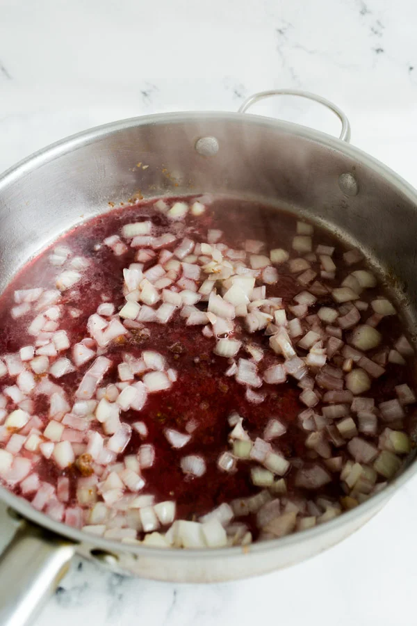 A skillet with chopped onions and red wine glaze