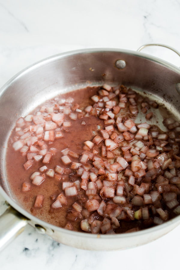 A skillet with chopped onions and red wine glaze