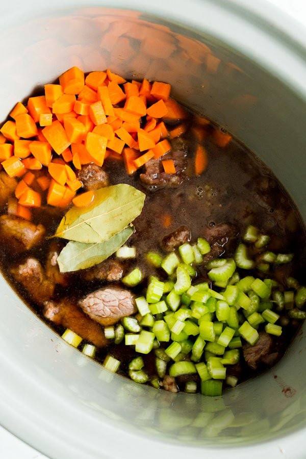 An overhead view of a crock pot in process for red wine beef stew